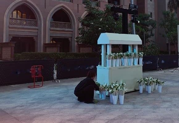 منسّق زهور يصفّ باقات التوليب الأبيض حول عربة الورد الكريمية