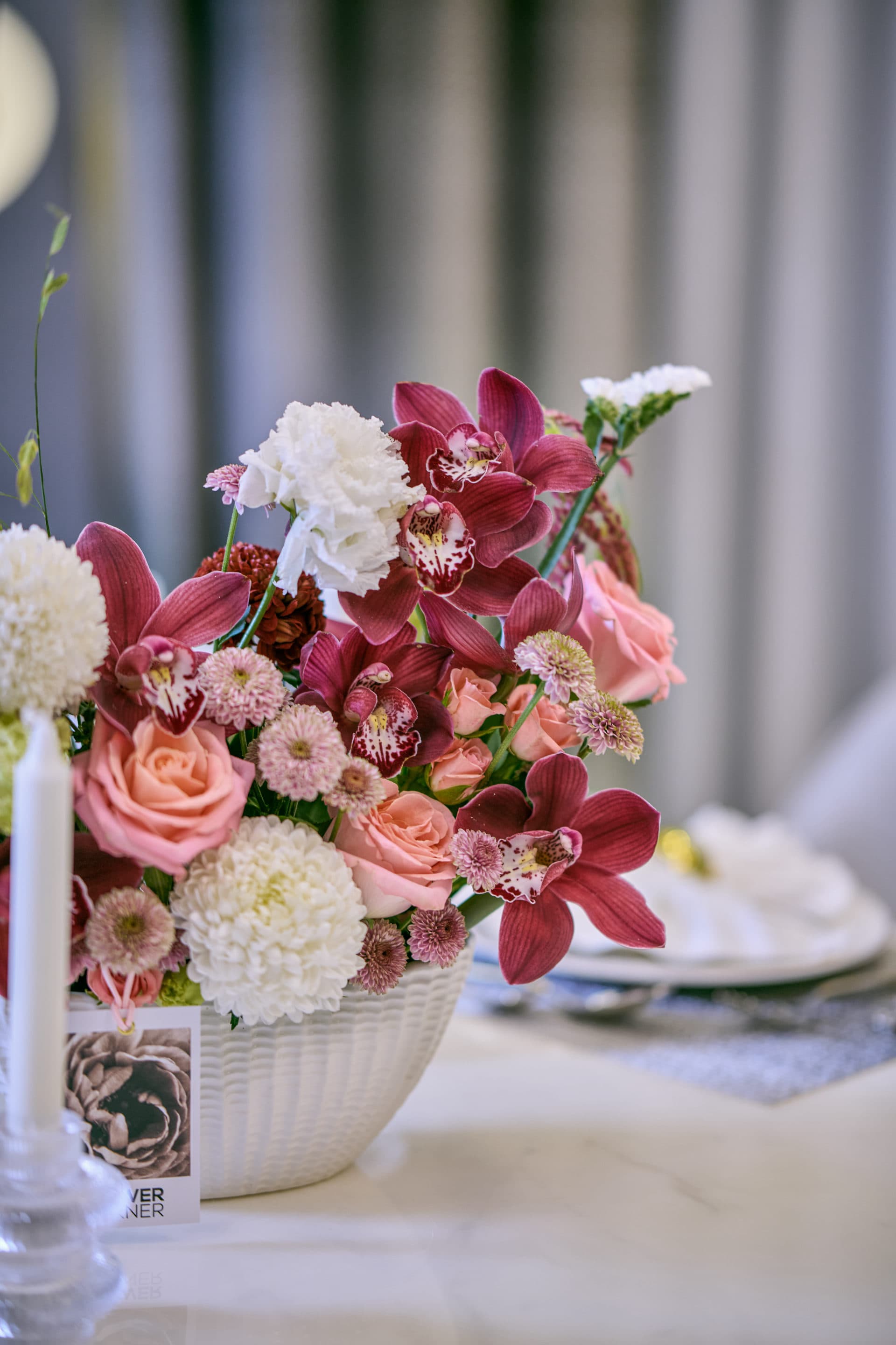 Deep red, pink and white wedding table centerpiece with taper candles at a Dubai reception, by Flower Corner — photo 1